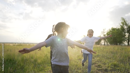 Children running in grassy field child and kid laugh while they play under warm sunlight in open grass field with friend and family nearby dog in distance natural energy and joyful movement.