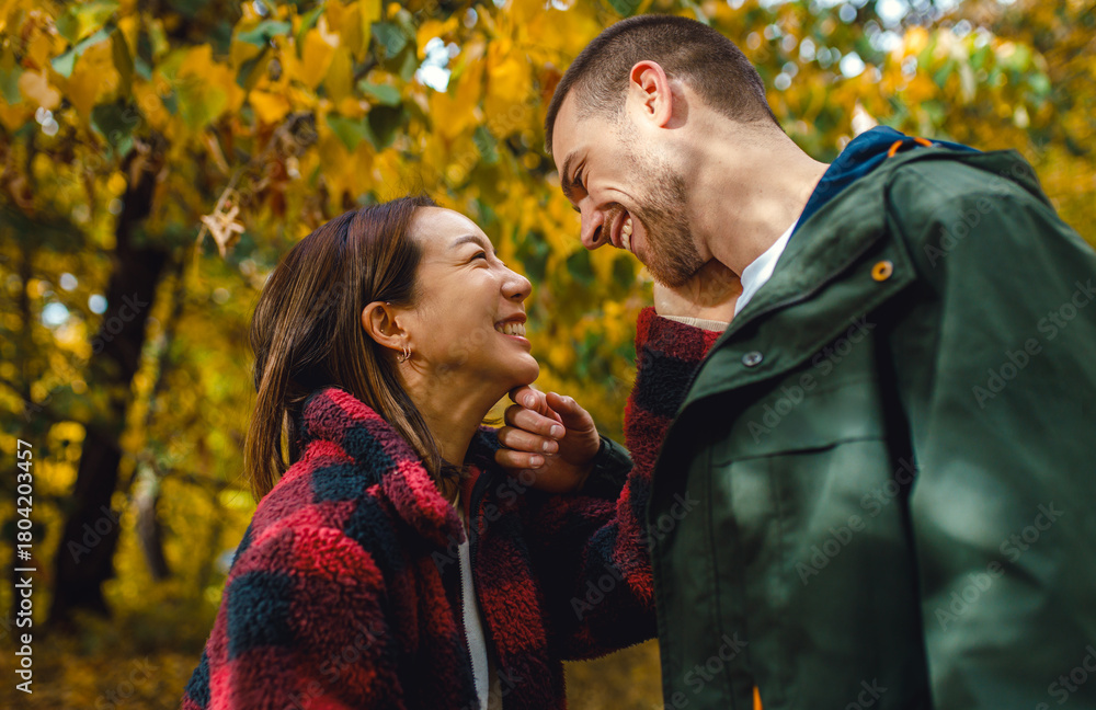 Fototapeta premium Smiling man and woman sharing a romantic intimate moment in an autumn park.