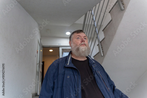 Elderly Caucasian man walking downstairs on his way out of the apartment building