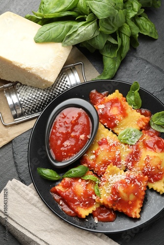 Delicious ravioli with tomato sauce, cheese, grater and basil on grey table, flat lay
