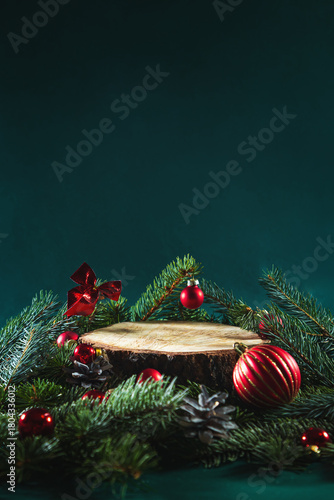 Wooden podium with fir branches and Christmas balls on a green background.