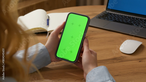 Woman use digital tech cell phone open green screen mock up. Hand press click phone web site middle center. Girl hold mobile. Turn on chroma key page. Cozy home background. Online app copy space.