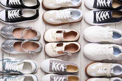 Fotografie Many stylish kid's shoes on grey wooden floor, flat lay