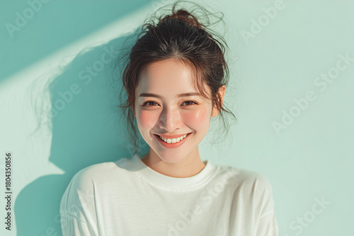 Smiling woman in white shirt with fresh natural light on mint green background
