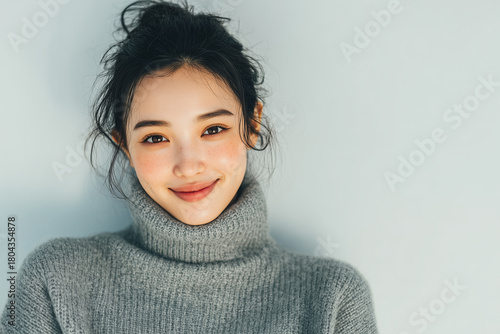 Smiling woman in gray turtleneck sweater on soft winter background
