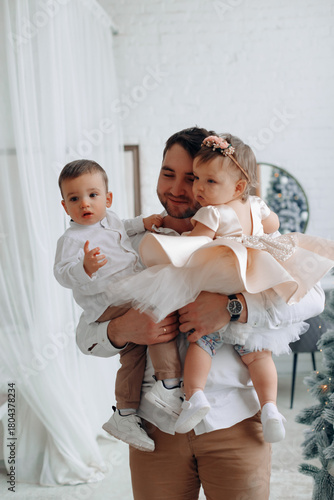 Father holding his children in a cozy indoor setting during a festive celebration in the morning light
