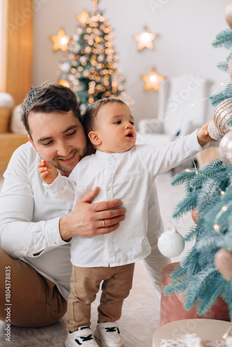 Father and son decorate the Christmas tree together in a cozy living room filled with holiday spirit and warm decorations
