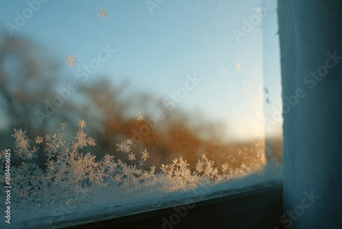 delicate white snowflakes gently rest on glass with warm glow of candle reflecting softly