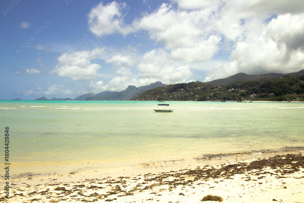 Obraz premium Anchored boat on tropical shoreline with mountains, Mahé, Seychelles