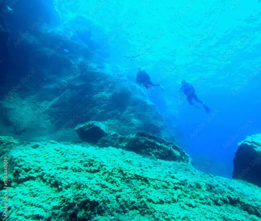 Naklejka premium two divers beginning the dive, near sea surface in mediterranea, seen from under the water