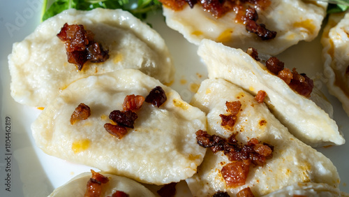 Polish pierogi with bacon bits on plate in natural light