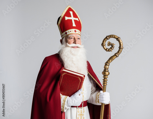 Postać Świętego Mikołaja biskupa z czerwoną mitrą na głowie, w czerwonym płaszczu, pastorałem w ręku i księgą w ręce