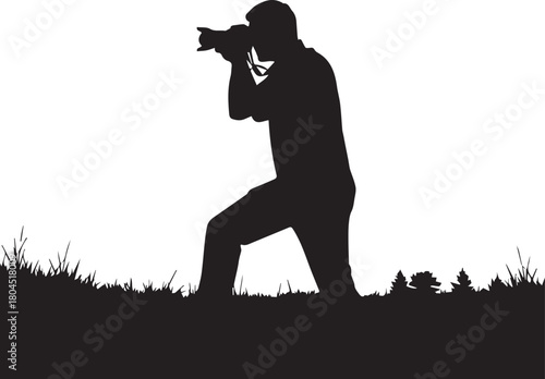 Silhouette of a photographer kneeling outdoors capturing a photo with professional camera