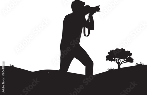 Silhouette of a photographer taking a picture of nature with a tree and grassy terrain