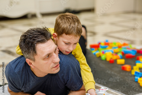 Obraz na plátne Loving father and son playing together on a luxurious tiled floor, embracing, la
