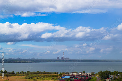 Power plant by lake under bright beautiful clouds