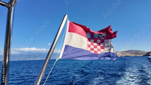 Croatian flag flutters in strong wind on boat journey across blue mediterranean sea