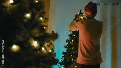 Man Decorates Christmas Tree With White Lights Ornaments While Dancing Happily