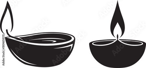 Two black diya oil lamps with flames on white background fire