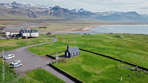 Drone view of Búðakirkja, Búðir, Iceland. Iconic black church with cemetery and surrounding mountains.