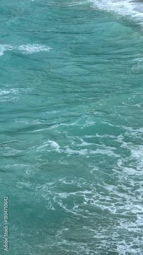 Powerful ocean waves  crashing and flowing in turquoise waters on a breezy day
