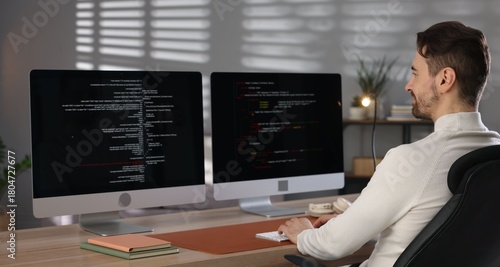 Canvas Print Programmer working on computer with dual monitors at table in office