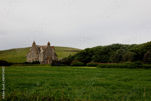 Abandoned ancient stone house in the wild Scottish Highlands, a remote ruined building surrounded by rugged moors, green fields, misty atmospheric landscape and dramatic overcast skies  rural Scotland