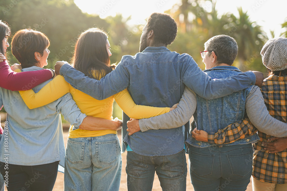 Obraz premium Group of multiracial people hugging each other at city park - Back view of multi generational community outdoor - Humanity, social inclusion and diversity concept