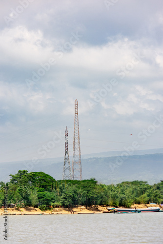 Nature and Industry: Tall Electric Transmission Towers Overlooking a Green Shoreline