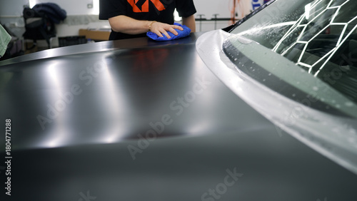Professional detailing service applying matte finish protective film on a car