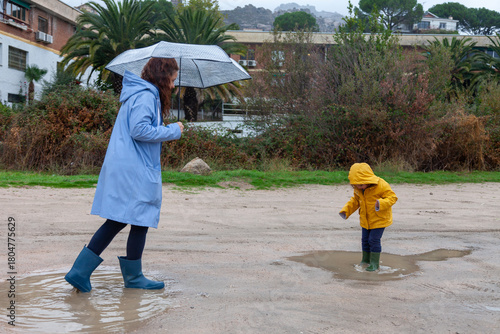 Authentic Family Moment: Young Mom and Her Little Girl Walking in the Rain.