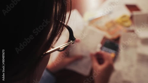 A housewife sits at desk, sorting receipts from stores, and calculating the family budget on a calculator. Concept of budget planning or tax return from home. High quality 4k footage