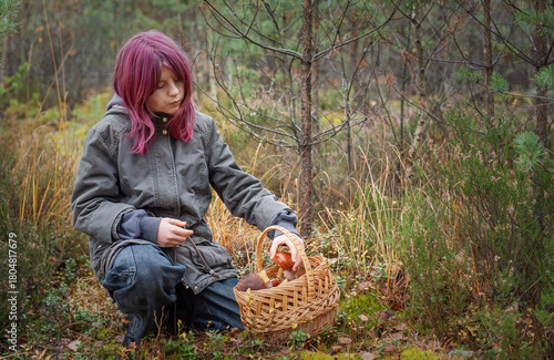 Young girl mushroom picking in autumn forest