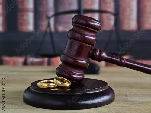 Slika na platnu Legal judgment symbolized by a gavel and wedding rings on a wooden base in a cou