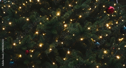 A close up view of a christmas tree with ornaments and string lights illuminating the scene