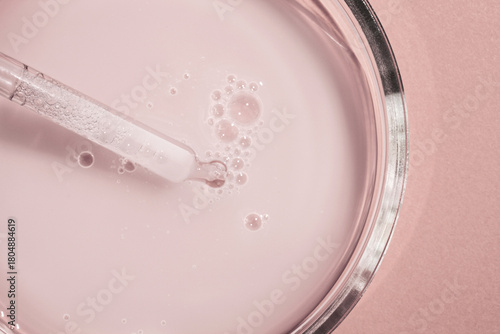 Liquid opaque pink milky gel with pipette on light pink colored background