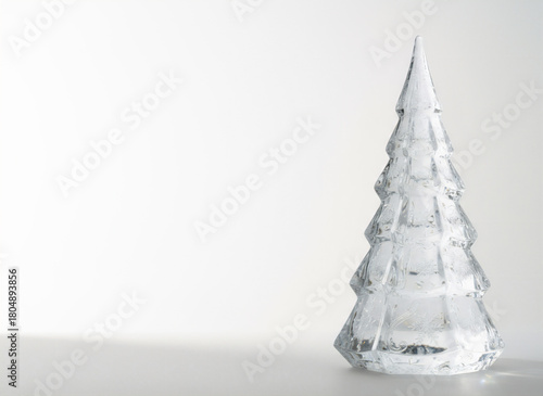 透明なガラスのクリスマスツリー　雪の結晶が刻まれたクリスタルオブジェのミニマル静物写真　冬のデザインや上品な季節素材に最適