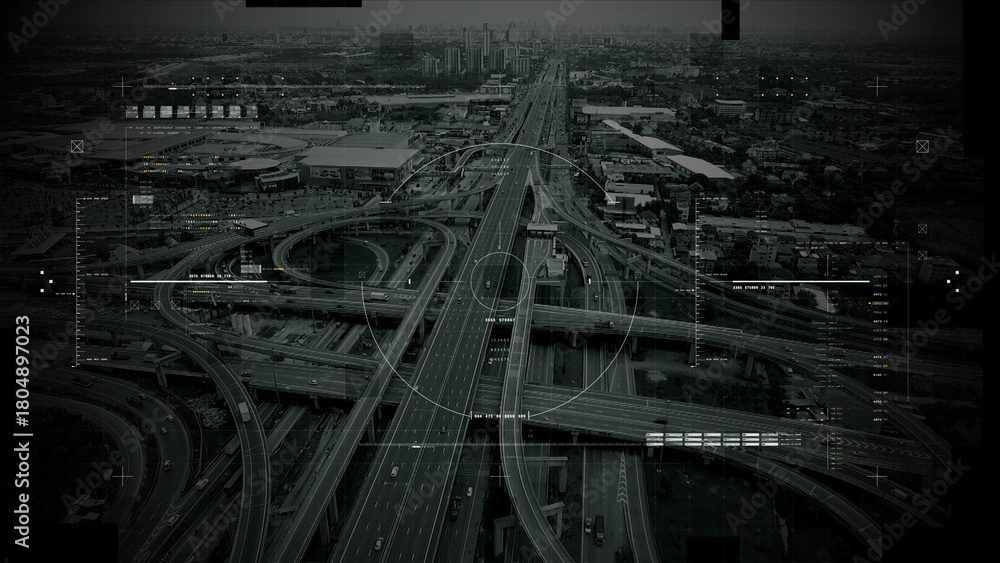 Fototapeta premium Aerial surveillance, military reconnaissance view of a complex highway interchange with HUD targeting graphics, creating a cinematic spy-drone atmosphere and intelligence-operation mood