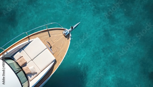 Aerial top view of luxury yacht bow with wooden teak deck on clear turquoise sea water. Cushions, pillows invite sunbathing on summer day. Rich boat trip for marine travel, vacation, leisure