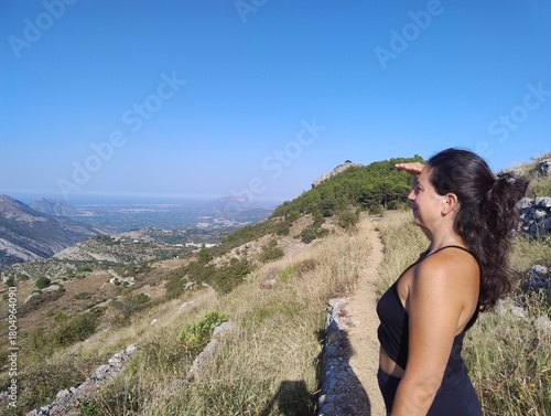 Woman Enjoying Scenic Mountain View on a Sunny Hiking Trail