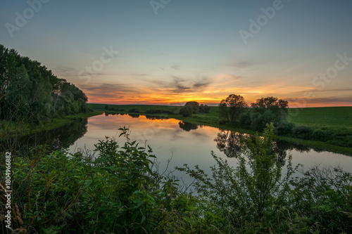 Calm sunset over a quiet river reflecting trees