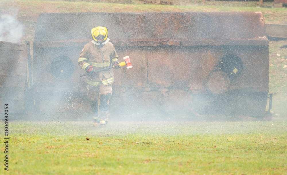 Fototapeta premium A firefighter run through Water mist and heavy smoke holding a rescue axe