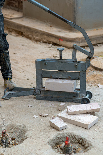 Canvas Print Construction worker using a manual block splitter to cut a paving stone