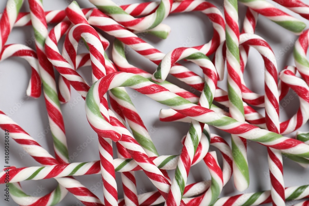 Fototapeta premium Tasty candy canes on grey background, flat lay. Christmas treat
