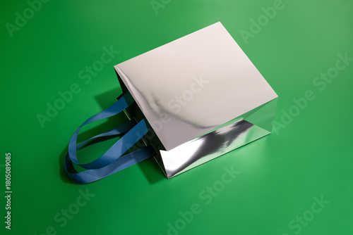 Silver metal paper glossy shopping bag mockup with blue handles	
