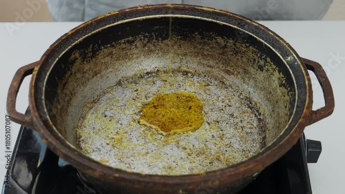Vegetable oil is poured into a frying pan over a fire. Medium shot.