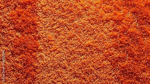 Close-up of a vibrant orange shag carpet texture. Plush, soft textile background with long fibers. Abstract home decor and flooring material