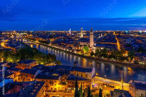 Night skyline of Verona with Adige river, Torre dei Lamberti and Basilica of Santa Anastasia, Italy. Architecture and landmark of Verona. Cozy cityscape of Verona.