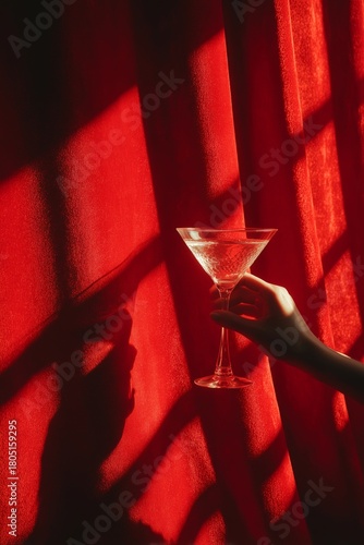 Thoughtful Moment With a Cocktail Glass Against Vibrant Red Curtains
