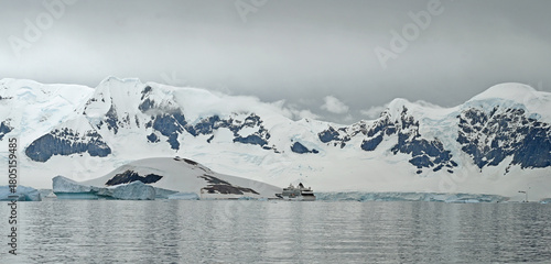 A crusie ship appears as a tiny boat in the Antarctic landscape.
